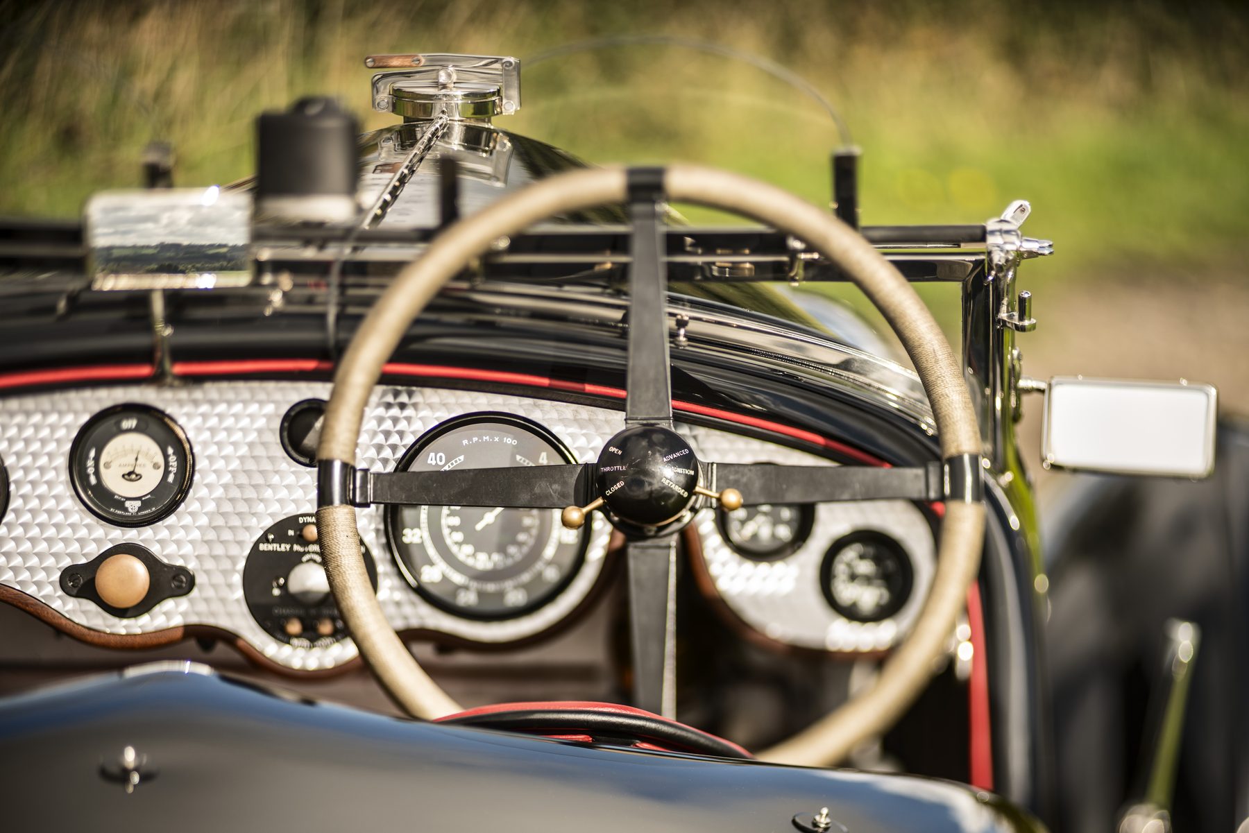 Engine-turned dashboard and cord-bound wheel seen through the aeroscreens in low sunlight