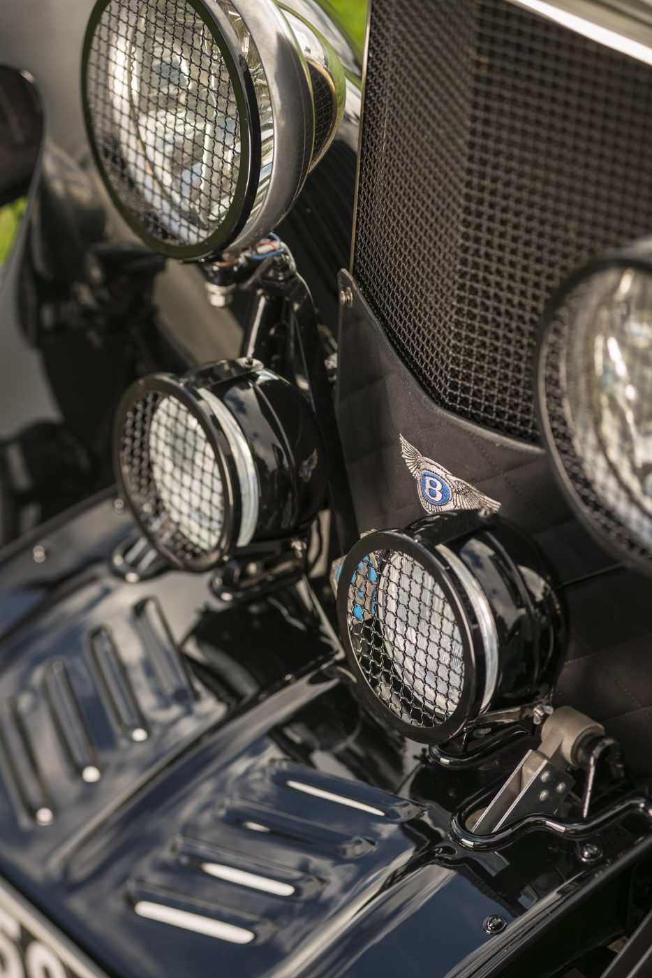 Close detail of mesh-guarded lamps and the Bentley badge on the quilted radiator apron