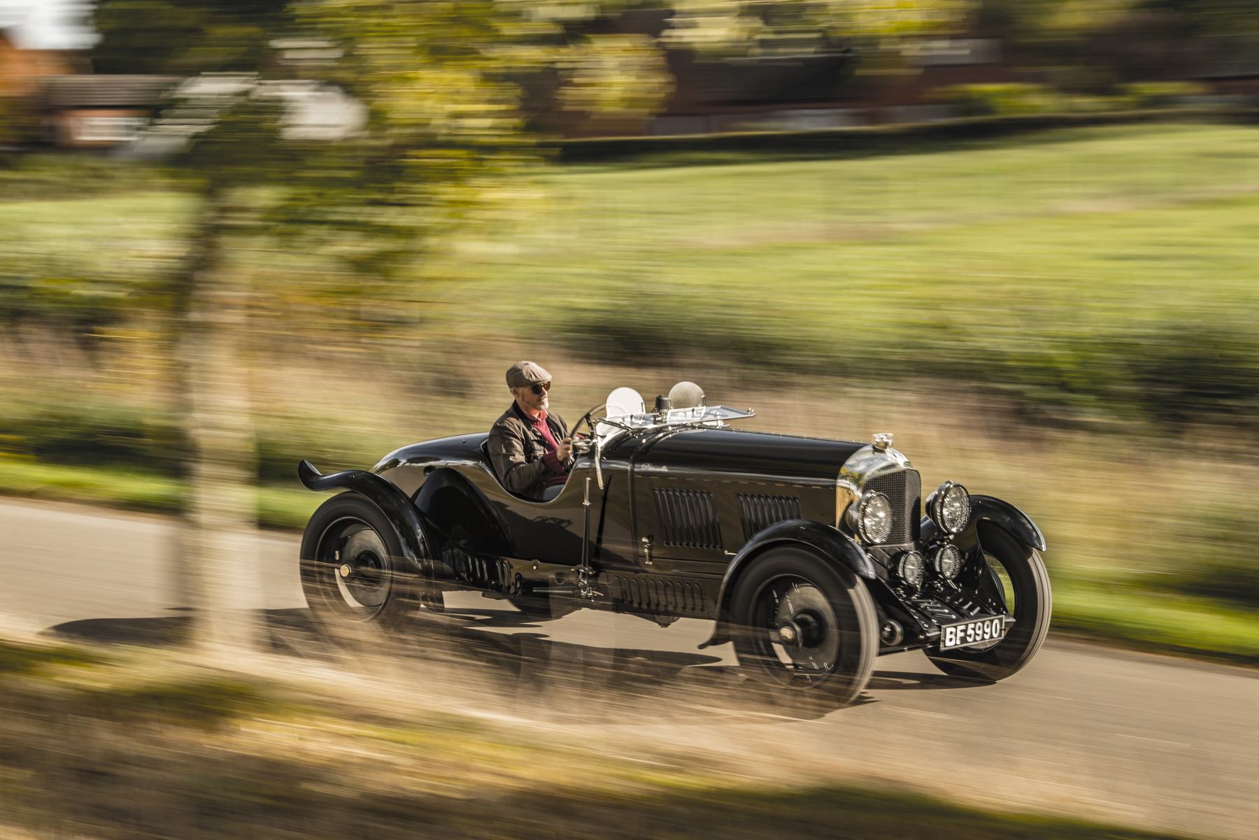 Side view of Petronella at speed past blurred hedgerows, driver at the wheel