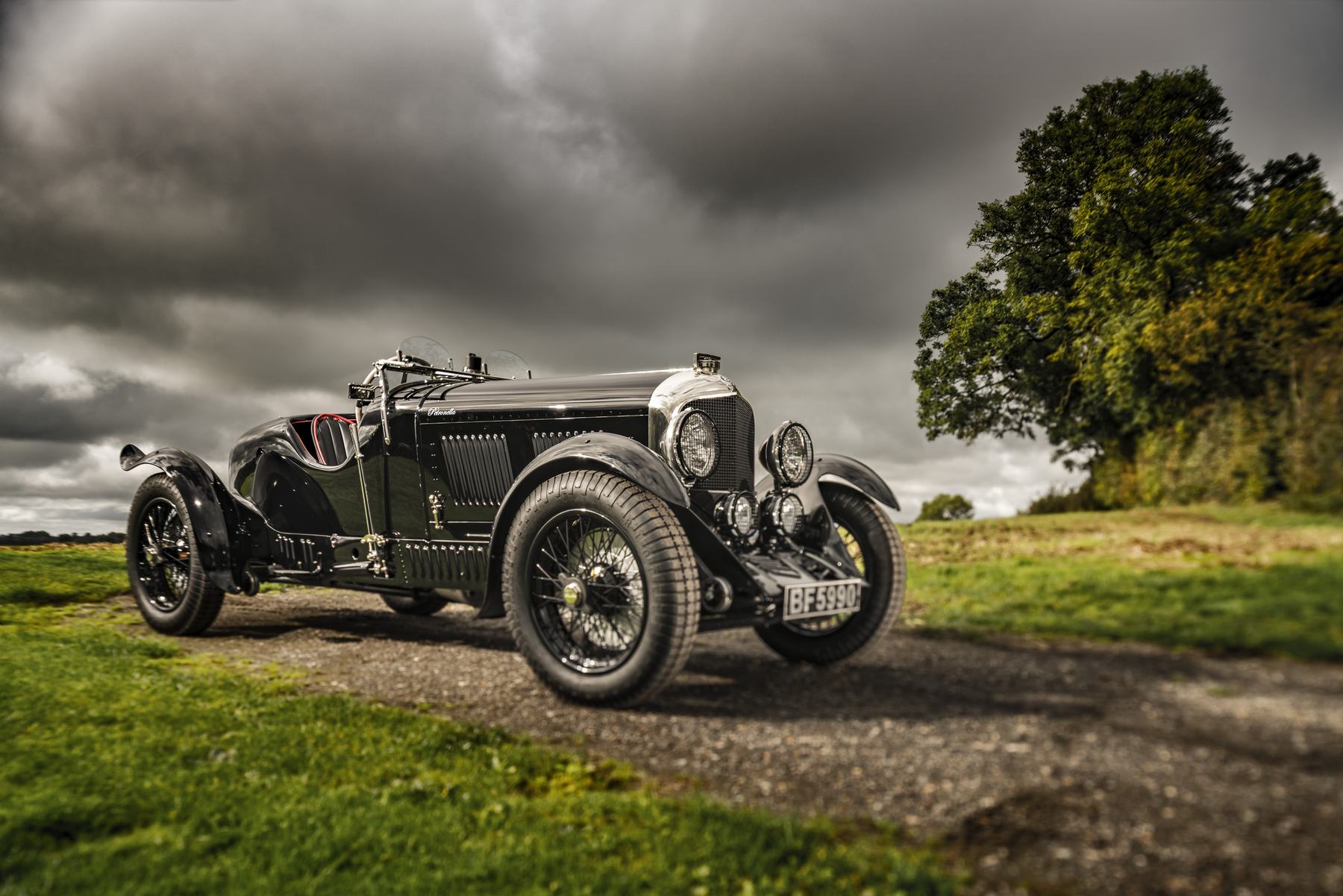 Front three-quarter view of Petronella on a gravel track under a dark storm sky